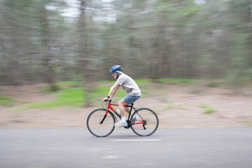 Naklejka premium Active senior pensioner outdoors active exercising wearing a bike bicycle helmet overcast bit of rain bike path riding a bike keeping busy during self isolation healthy 
