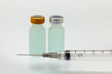 Isolated two plastic vaccine bottle with colored liquid and needle syringe very close high magnification mockup