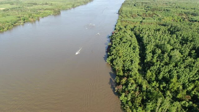 Vista a&eacute;rea de un ancho r&iacute;o con &aacute;rboles en la costa y barcos navegando. 