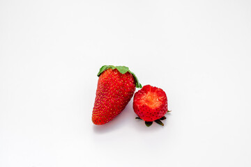 2 isolated strawberries, one berry has a bite taken from it.