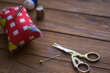 Sewing items on a wooden table. Bird-shaped scissors.