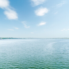 Naklejka premium blue river and sky with white clouds over it