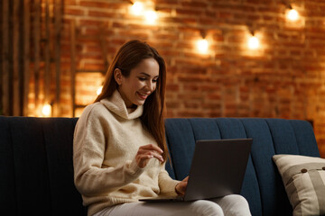 Working from home.Communication online with colleagues and freelancers.Portrait of young female freelancer using laptop and smiling. Concept of young people working with mobile devices.