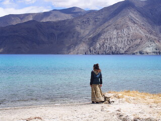 Fototapeta na wymiar A woman looking out at a beautiful lake, Pangong tso (Lake), Durbuk, Leh, Ladakh, Jammu and Kashmir, India