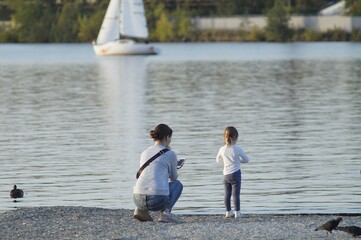 Serene family vacation on the background of the water and yachts. Mom and daughter spend time on the lake.