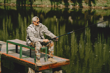A man fishing on a lake. Guy in a uniform.