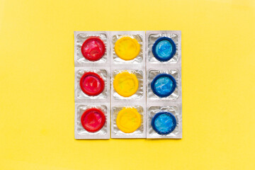 Composition with colorful condoms on yellow background. Safe sex and contraceptive concept. Flat...