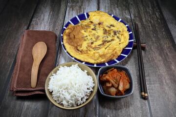 Fried egg with sliced onion and pork sausage on the plate. Famous breakfast menu serving with cooked rice in Asia restaurant. 