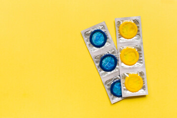 Composition with colorful condoms on yellow background. Safe sex and contraceptive concept. Flat lay, top view, copy space.