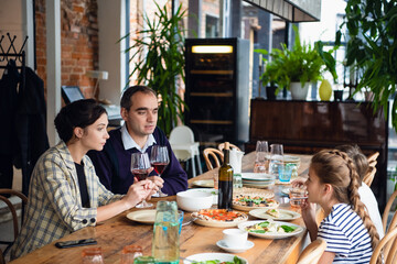 A family of four raising glasses at dinner in a cafe.