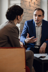 Two people discussing bussiness questions in an informal setting. The man is gesturing while talking.