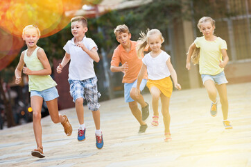 Fototapeta na wymiar Group of smiling glad children running outdoors in city street on good weather