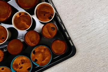  Easter cakes, with raisins, in small round shapes. On the black oven tray, on the left, is a fragment of the corner.