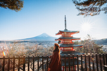 Pretty Girl standing Behind at Beautiful view of mountain Fuji and Chureito pagoda, Fujiyoshida, Japan. Backgound of Fuji Autumn leaves during sunset with clear blue sky. - obrazy, fototapety, plakaty