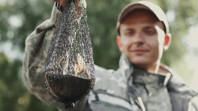 Men's hobby concept. Closeup of a man fisher who caught a fish in an ambush net and looking at it