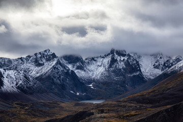 Obraz premium Beautiful View of Scenic Alpine Lake and Snowy Mountains in Canadian Nature. Season change from Fall to Winter. Aerial Shot. Taken near Grizzly Lake in Tombstone Territorial Park, Yukon, Canada.