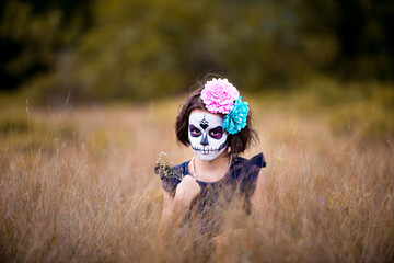 Young girl sugar skull facepaint with flower on Halloween.