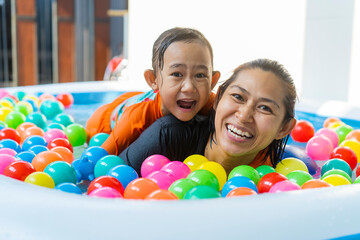 Fototapeta na wymiar Asian Mother and daughter playing with in the pool at house and coloured balls