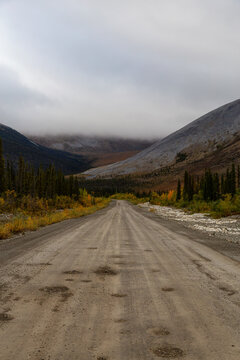 View of Scenic Road, Trees and Mountains on a Cloudy Fall Day in Canadian Nature. Taken near Tombstone Territorial Park, Yukon, Canada.