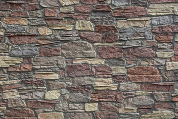 texture of the building facade is made of colored masonry, blocks of different sizes and shapes. Texture of the walls of the building for design