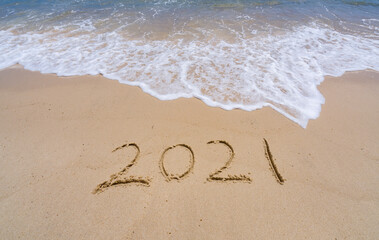 2021 year message handwritten in sand on beautiful beach background. New Years concept.
