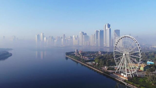 View from above of Sharjah's Khalid Lake, Eye of Emirates, Sharjah Skyline on a foggy morning, United Arab Emirates, 4K video
