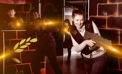 Two laser tag players of different nationalities aiming laser guns at other players during lasertag game in dark room