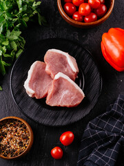 Fresh pork tenderloin on a black plate