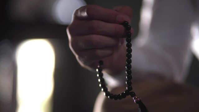 Hand of Muslim man making zikr using rosary (praying to Allah)