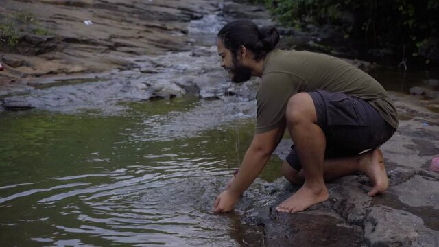 vivek bearded long hair man washing face in fresh water in jungle