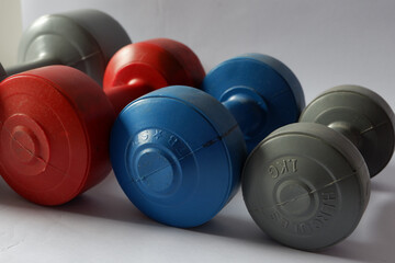 Various sizes and colors of barbells on a white background