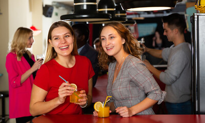 Two young women with cocktails having fun on party at nightclub. High quality photo