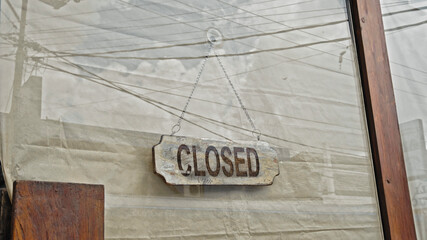 A sign hanging on a door with a glass window with the inscription closed