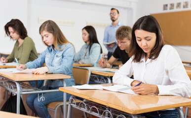 Obraz premium Girl is writing test and answer about task in the classroom.