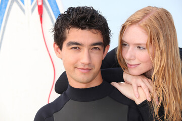 Young surfing couple in wetsuits