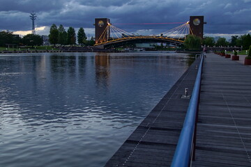 City night park in early autumn with pavement, young green leaves and trees and river. Landscape, Japan.