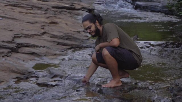 vivek bearded long hair man plaing in river water  in jungle water