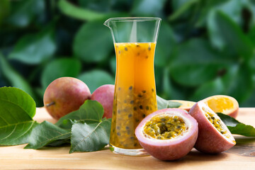 Passion fruits half and juice on green leaves background.