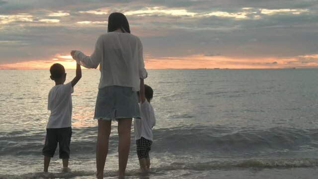 An Asian family was happily strolling the beach at sunset.