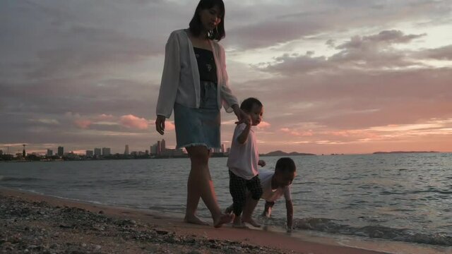 An Asian family was happily strolling the beach at sunset.