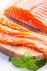 Raw fresh salmon fillet cut into slices and piece on wooden board
