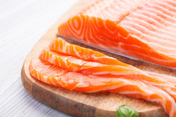 Raw fresh salmon fillet cut into slices and piece on wooden board