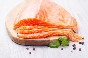 Raw fresh salmon fillet cut into slices and piece on wooden board