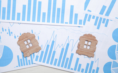 Wooden house models on financial graphs.