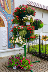 Fototapeta na wymiar Iron stand with many flower pots with different blooming flowers