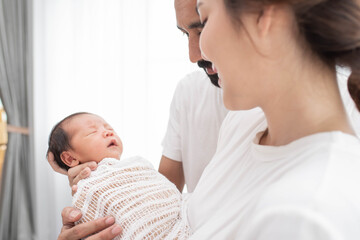 smiling mother and father holding their newborn baby at home..portrait of happy family at home, young parents holding on hands little sweet newborn baby, love and happiness concept.