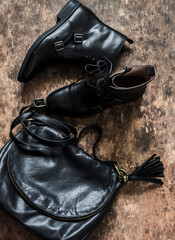 Black leather shoes, black leather bag on a wooden background, top view. Fashion concept
