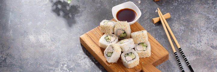 Roll made of Fresh cucumber and chicken and salad inside in a gray background. Delicious food. Beautiful still life with a portion of rolls on a wooden board.