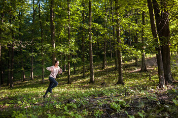 Naklejka na ściany i meble Young woman wearing yoga pants runing in the woods on a sunny morning.