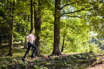 Young woman wearing yoga pants meditating in the woods on a sunny morning.